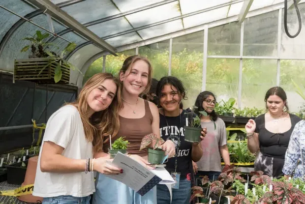 一群学生在温室里挑选他们一年级的植物.