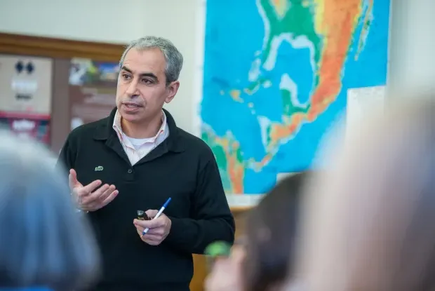 A professor teaching in front of a map.